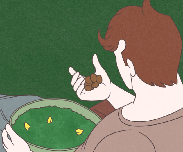 A view from over Cillian's left shoulder as he holds a handful of acorns over his salad bowl.