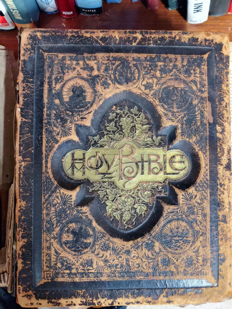 An ancient hardcover Holy Bible, dingy with color peeling away from the raised patterns.