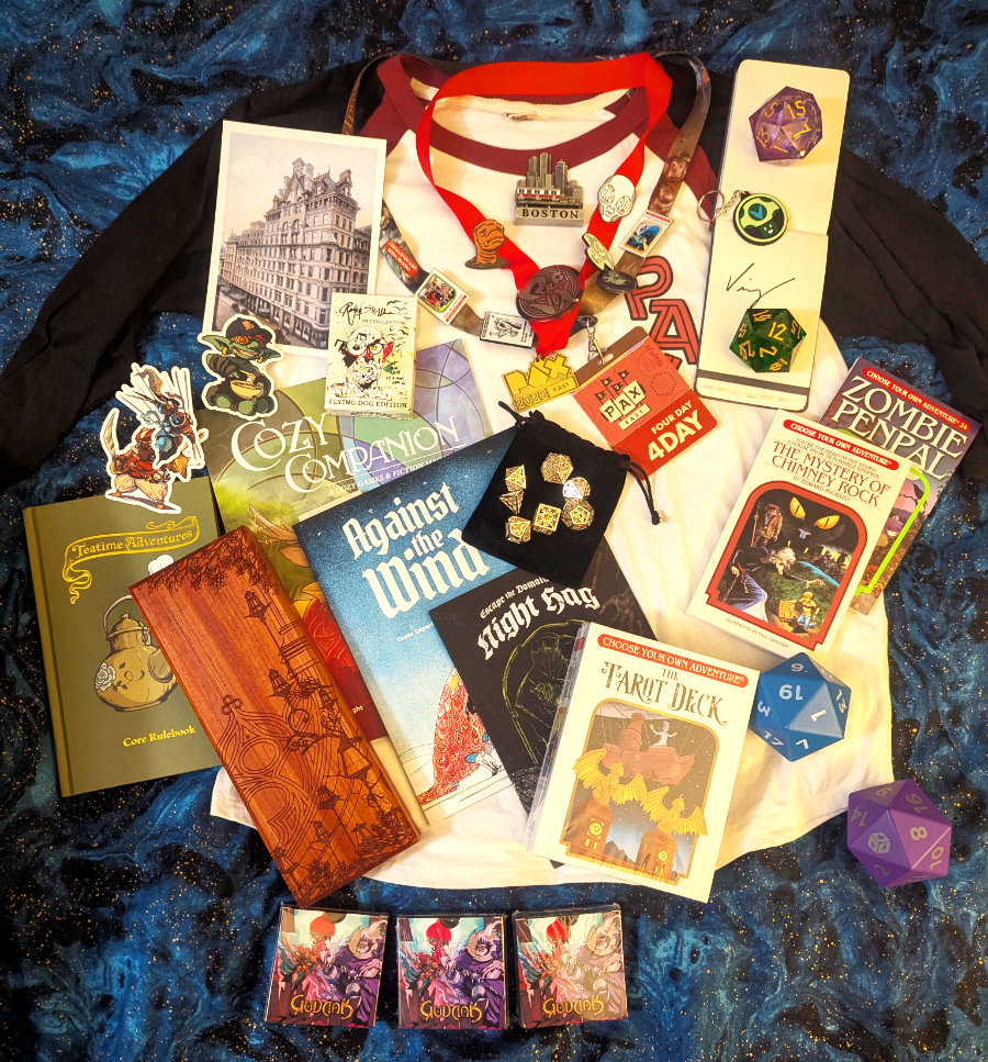 An assortment of goods procured from PAX East, including foam dice, a seven metal dice set, a PAX shirt, a badge and lanyard with pins, a vintage postcard of the Omni Parker Hotel, stickers, a wooden dice box, solo RPG books, playing cards, cozy gaming magazines, CYOA adventure books, a CYOA tarot deck, three giveaway decks of a card game I'll probably never play, two giant resin d20 dice, and an autograph. The Boston train souvenir magnet somehow made its way in there.