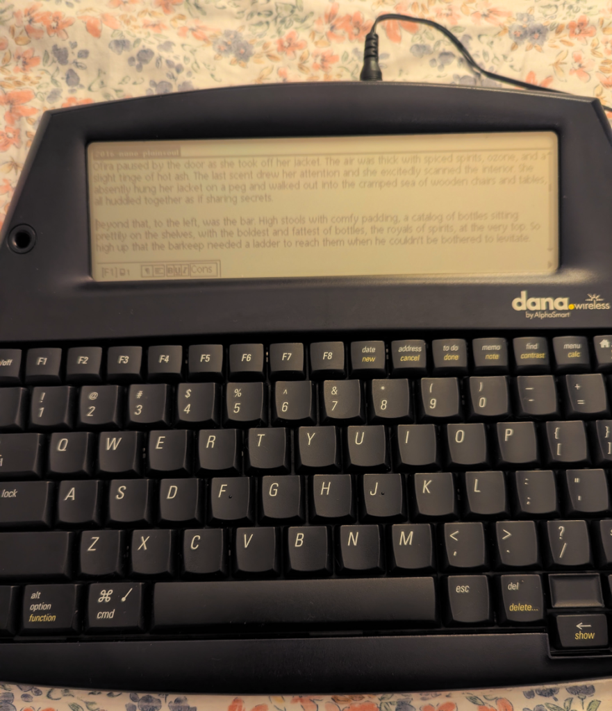 The AlphaSmart Dana plugged in, showing a sample of text on the screen.